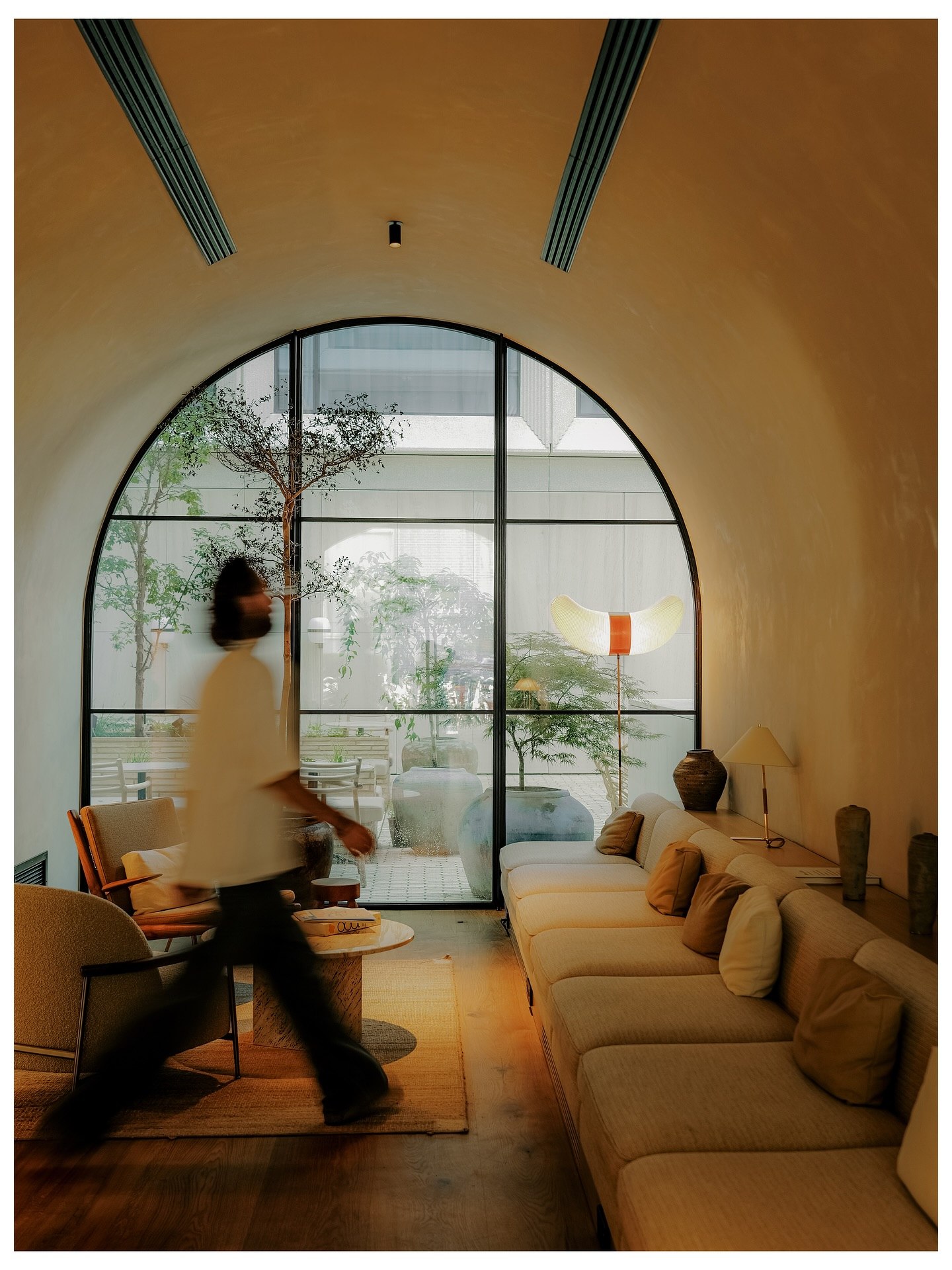 Hotel lounge under a vaulted ceiling with an arched window onto the courtyard