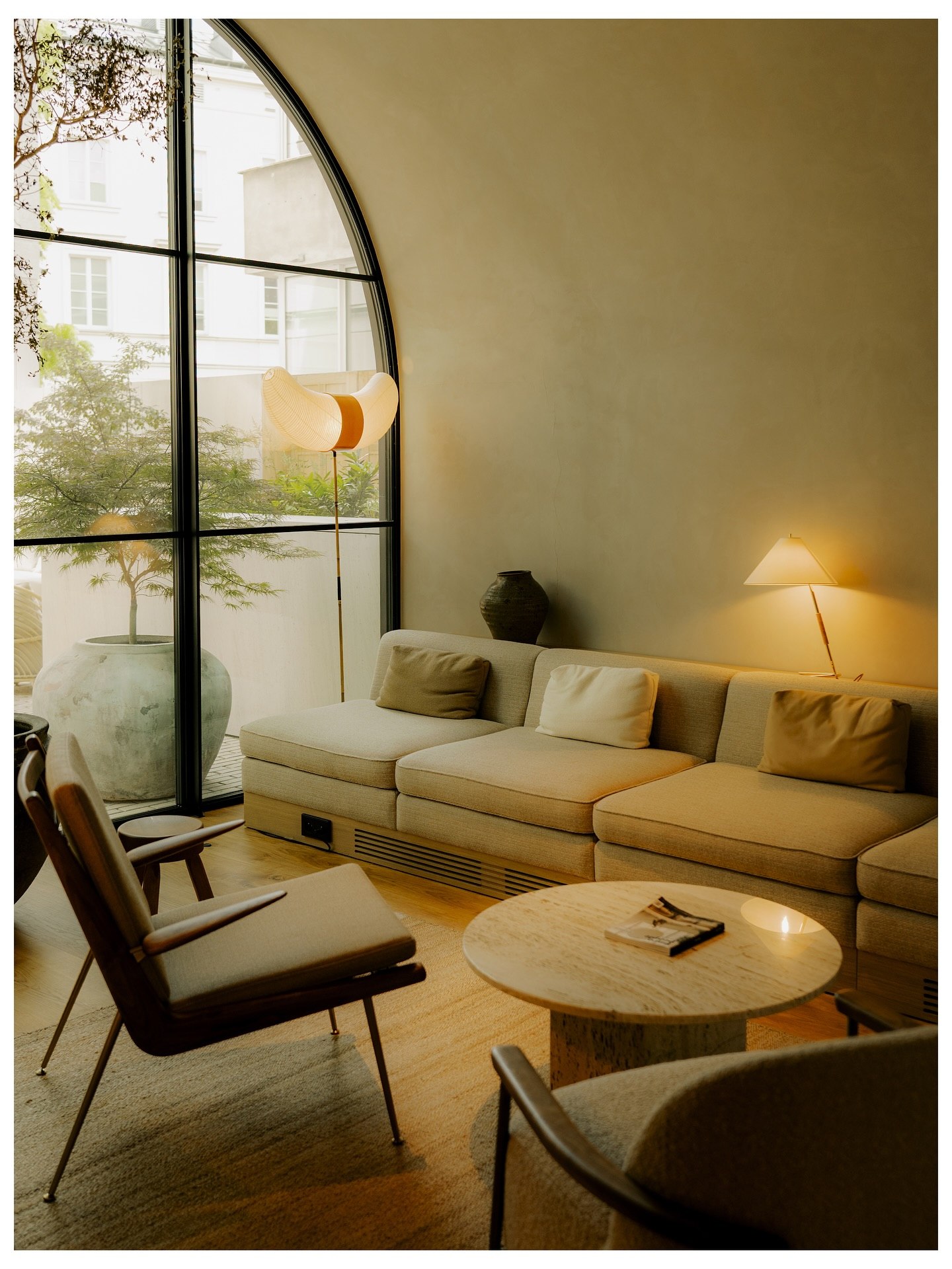 A hotel lounge under a vault, with an arched window onto a planted courtyard