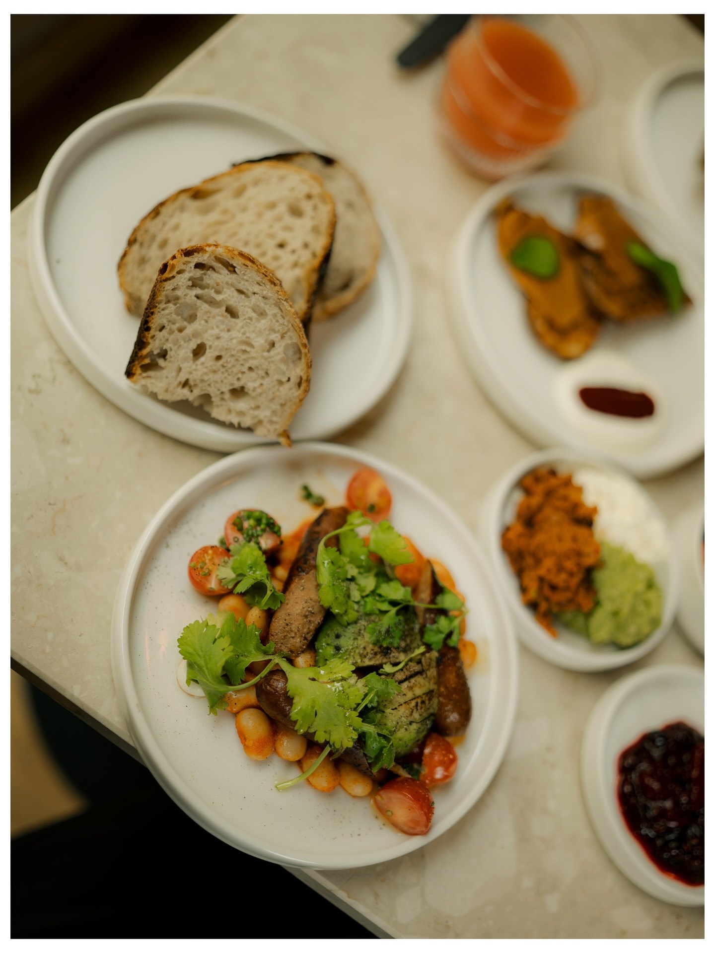 A breakfast spread of sourdough, small plates and juice on a marble table